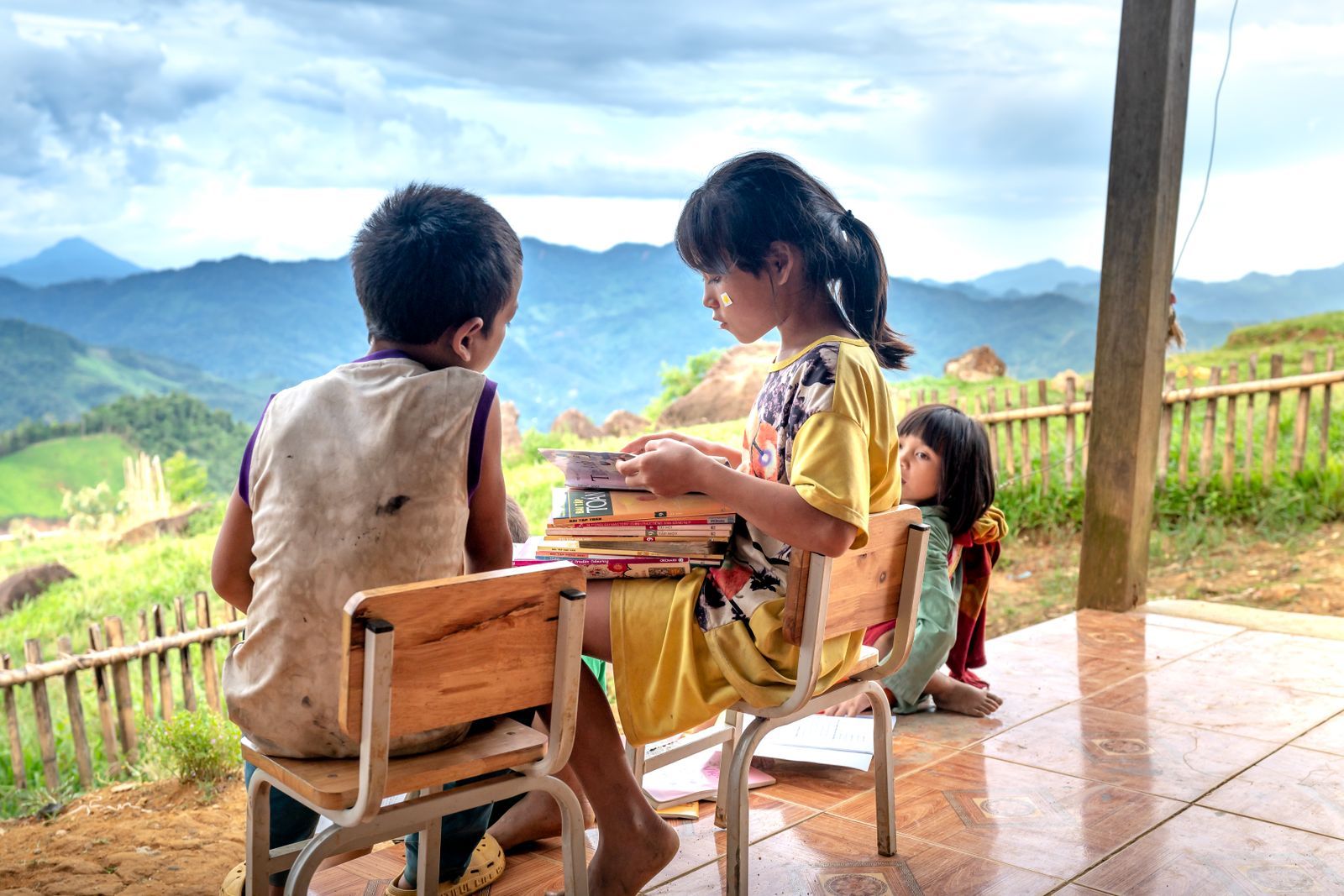 Two children reading together on a porch